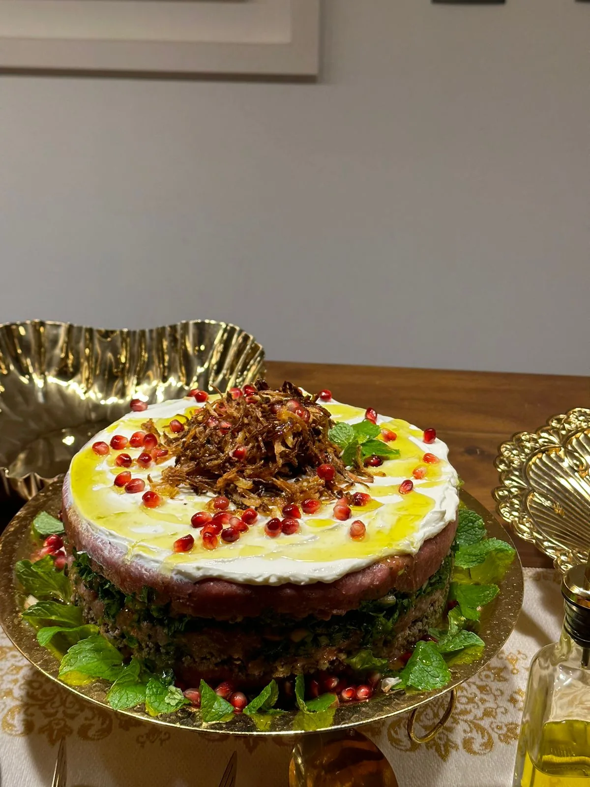 Torta de kibe cru em suporte dourado ornamentado com romã